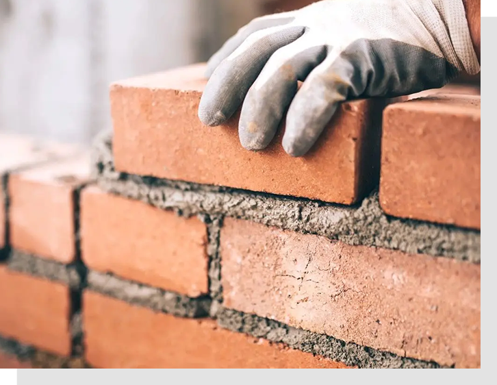 A person in gloves is building a brick wall.