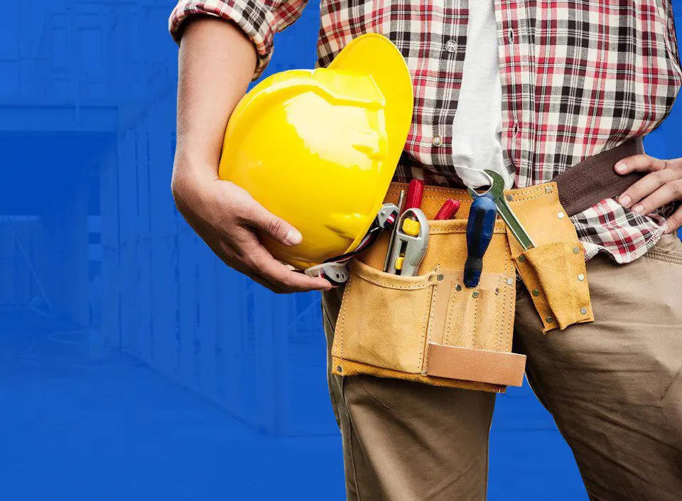 A man holding a yellow hard hat and tools.