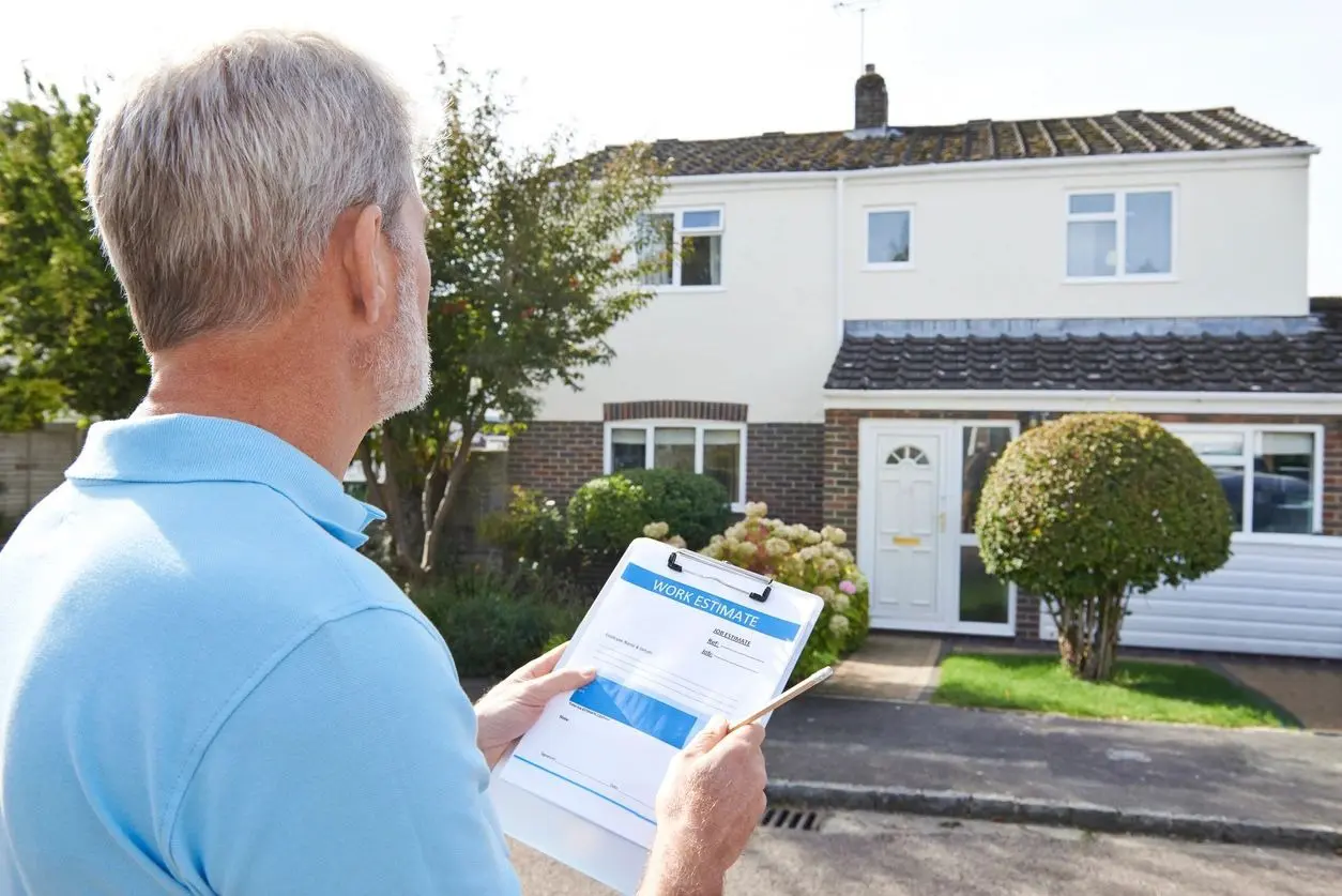 A man holding papers in front of a house.