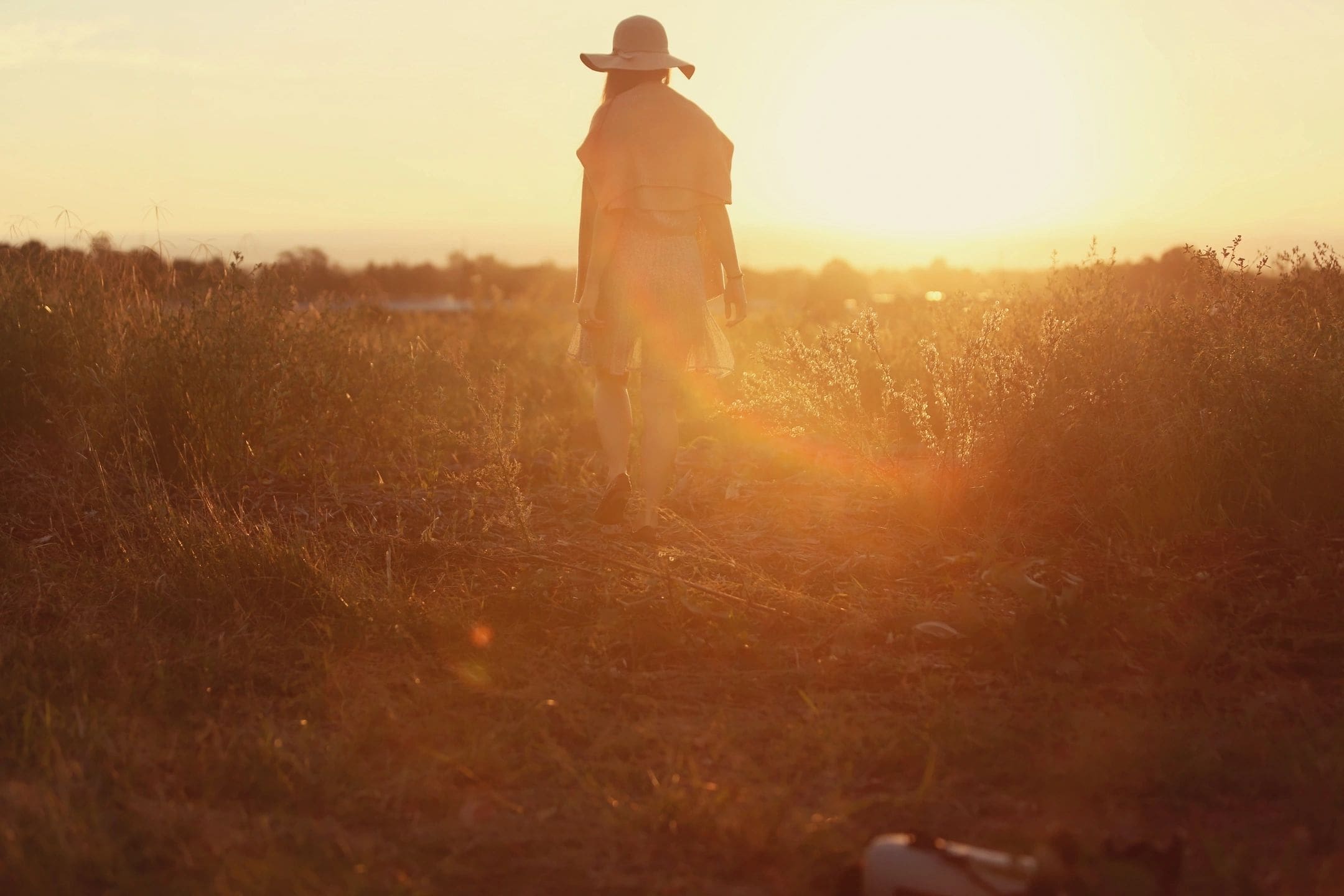 A person standing in the grass at sunset.